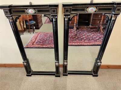 Pair of ebony pier mirrors with porcelain plaques